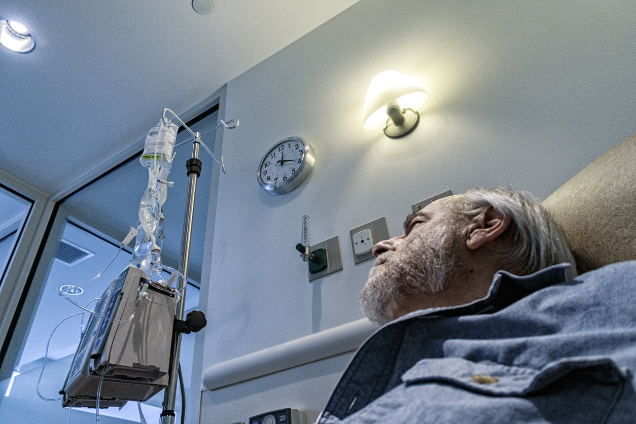 Senior male cancer patient looking at his IV bag.