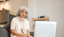 Woman watching webinar taking notes